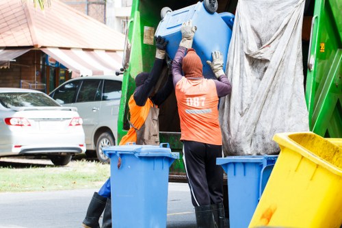 Insured waste removal operatives loading office furniture into a vehicle